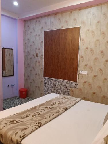 a bedroom with a bed with a wooden board on the wall at The Rainbow Residency guest house in Varanasi