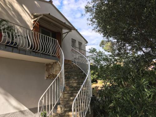 a white building with stairs next to a tree at Les Meublés de la Corniche in Argelès-sur-Mer