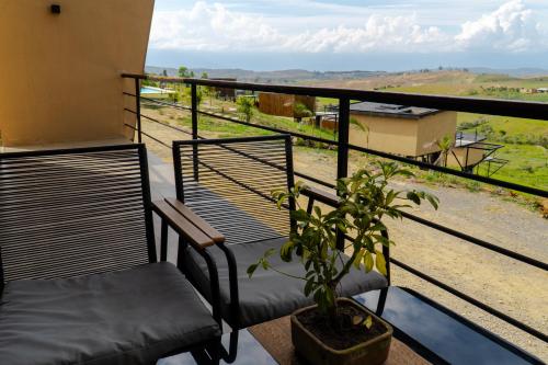a balcony with two chairs and a potted plant at Oasis Barichara in Barichara