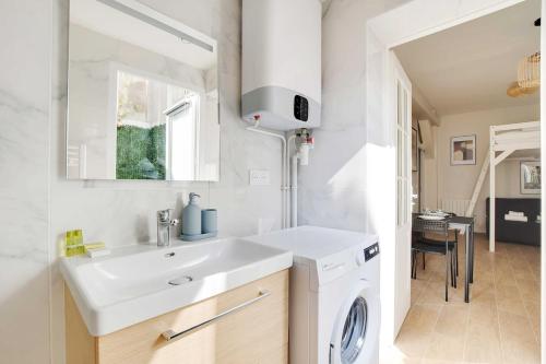 une salle de bain avec un lavabo et une machine à laver dans l'établissement Cozy apartment with garden near République, à Paris