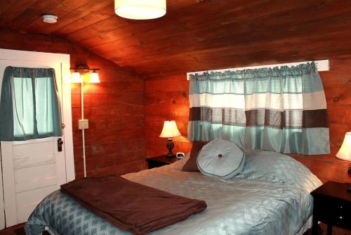 a bedroom with a bed in a room with wooden walls at Family Cabin Rental on Beautiful Ranch near Yellowstone National Park, Wyoming in Wapiti