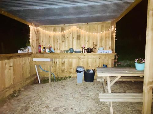 a wooden shed with a picnic table and lights at Luxury Stargazing Glamping - Seren Aur with Hot Tub in Llanidloes