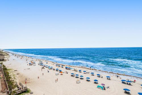 a beach with people and umbrellas and the ocean at Island Royale 602 in Gulf Shores