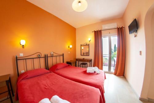 a bedroom with two beds with red sheets and a window at Taxi Driver Apartments in Paleokastritsa