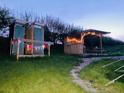a cabin with a string of flags in a field at Luxury Stargazing Glamping - Seren Aur with Hot Tub in Llanidloes
