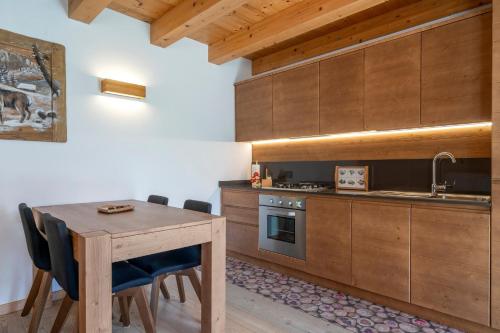 a kitchen with wooden cabinets and a wooden table and chairs at GuestHost - Sappada Lovely Lodge in Sappada