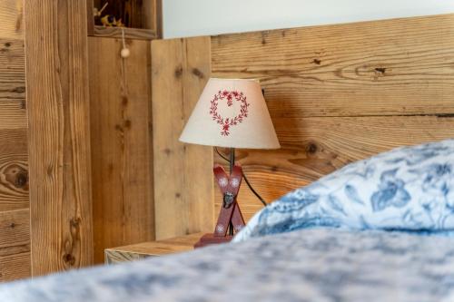a lamp sitting on a table next to a bed at GuestHost - Sappada Lovely Lodge in Sappada