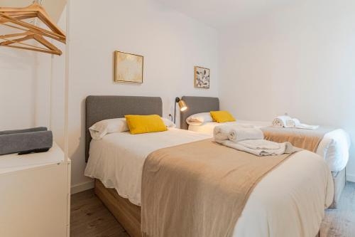 a bedroom with two beds with yellow pillows at RentitSpain - Playa Granada - Apartamentos TRM Aguacate Relax entre Mar, Golf y Montaña in Motril