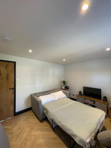 a bedroom with a bed and a flat screen tv at Evergreen Cottage in East Preston