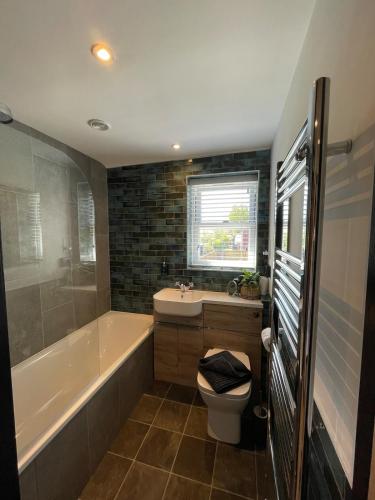 a bathroom with a tub and a toilet and a sink at Evergreen Cottage in East Preston