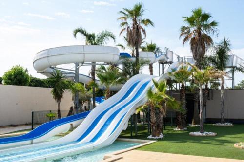 - un toboggan aquatique dans un complexe avec des palmiers dans l'établissement Belle villa d'angle climatisée dans domaine de vacances PORTES DU SOLEIL, 3 chambres, 6 couchages, fibre Wifi, à PORTIRAGNES PLAGE LRPDSH5, à Portiragnes