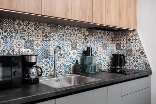 a kitchen with a sink and a tile back splash at Nowy Hotel Monika - by Upstairs in Kraków