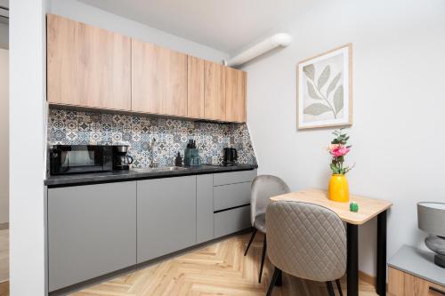 a kitchen with white cabinets and a small table at Nowy Hotel Monika - by Upstairs in Kraków