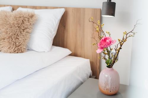 a vase with flowers on a table next to a bed at Nowy Hotel Monika - by Upstairs in Kraków