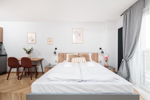 a white bedroom with a bed and a table at Nowy Hotel Monika - by Upstairs in Kraków