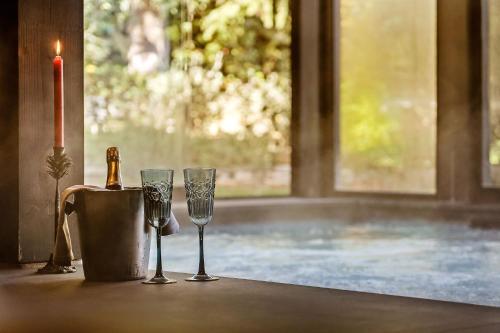 a table with two wine glasses and a candle at I Capricci Di Merion - Resort & Spa in Tuoro sul Trasimeno