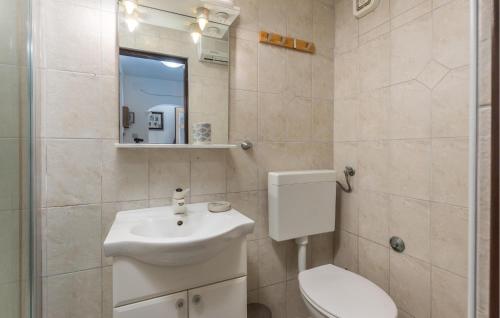 a bathroom with a sink and a toilet and a mirror at Awesome Home In Lopar With Wifi in Lopar