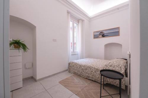 a white bedroom with a bed and a chair at Santa Caterina Apartment in Varazze