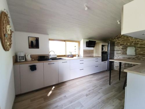 - une cuisine avec des placards blancs et un mur en pierre dans l'établissement Le petit Boudou, à Riec-sur-Bélon