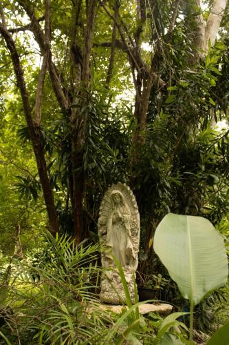 a statue sitting in the middle of a forest at El Prado- Rancho familiar en Yucatán in Xocchel