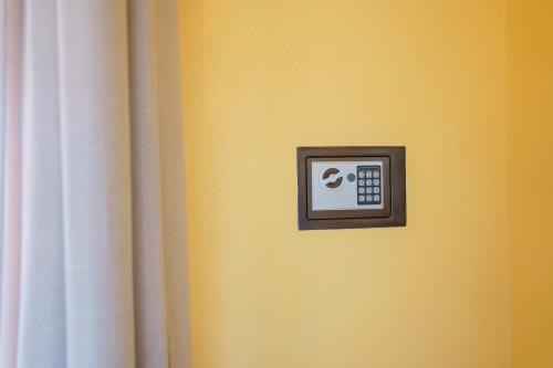 a clock on a yellow wall next to a curtain at Paradise Home in Quartu SantʼElena