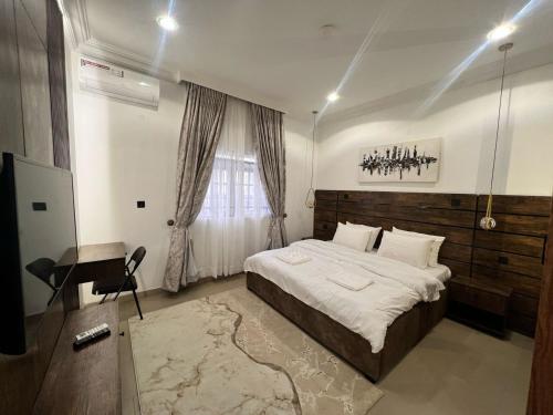 a bedroom with a bed and a desk and a window at Blue Velvet Apartments II in Abuja