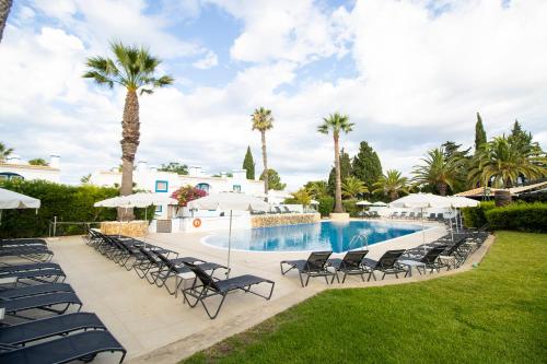 a resort pool with chairs and palm trees at Pestana Palm Gardens in Carvoeiro