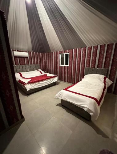 two beds in a room with red striped walls at Arena Desert Camp & Adventurers in Wadi Rum