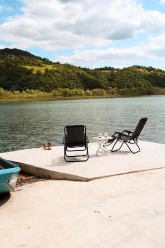 two chairs and a table on a dock on a body of water at Drina River Retreat in Novo Selo