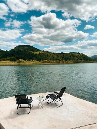 two chairs and a table on a dock near the water at Drina River Retreat in Novo Selo