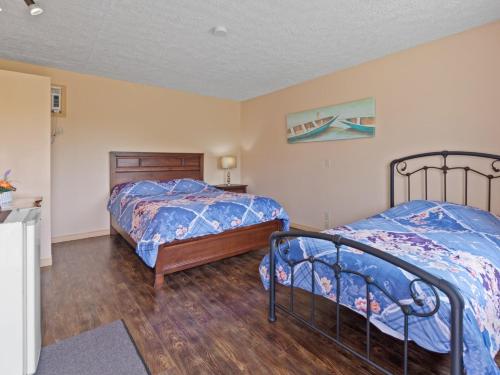 two twin beds in a bedroom with wood floors at Motel la Maison de Travers in Baie-Sainte-Catherine