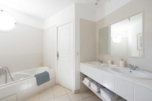 a white bathroom with two sinks and a tub and a mirror at Villa Les Mimosas, Fayence in Fayence