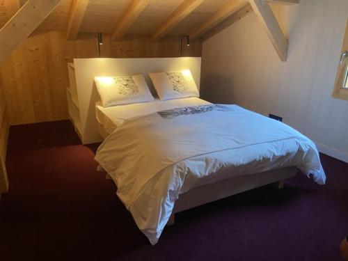 Un dormitorio con una cama con sábanas y almohadas blancas. en Les Carroz de Mary - Sommand, en Mieussy