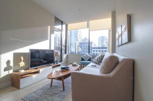a living room with a couch and a tv at Beautiful Downtown Unit in Vancouver