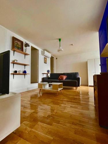 - un salon avec un canapé noir et du parquet dans l'établissement Large 2-Room Air-Conditioned with Terrace - Near Train Station, à Toulouse