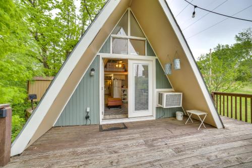 a small house with a pitched roof with a patio at Walk to Lake Taneycomo Cabin with Deck and Fire Pit! in Rockaway Beach