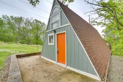 a green and orange garage with an orange door at Walk to Lake Taneycomo Cabin with Deck and Fire Pit! in Rockaway Beach
