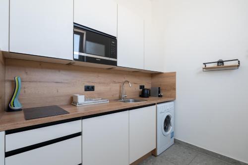 a kitchen with white cabinets and a washer and dryer at Vienna Stay Apartments Schönbrunn in Vienna