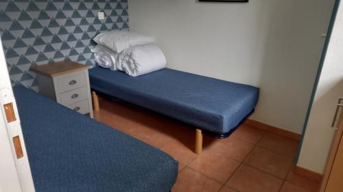 Cette petite chambre comprend un lit bleu et une table. dans l'établissement T2 32m2 terrasse 8m2 PISCINE LACANAU OCEAN LAC GOLF MULTISPORT, à Lacanau-Océan
