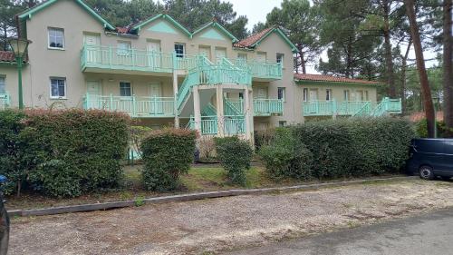 ein großes Haus mit grünen Balkonen an der Seite in der Unterkunft T2 32m2 terrasse 8m2 PISCINE LACANAU OCEAN LAC GOLF MULTISPORT in Lacanau-Océan