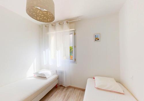 une chambre blanche avec un lit et une fenêtre dans l'établissement LILAS - Appartement pour 4 à proximité des commerces, à Capbreton