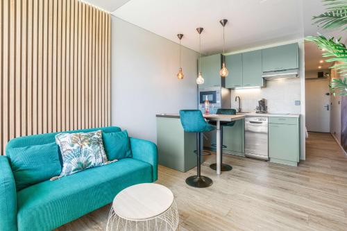 un salon avec un canapé bleu et une cuisine dans l'établissement Emeraude Port Nature, au Cap d'Agde