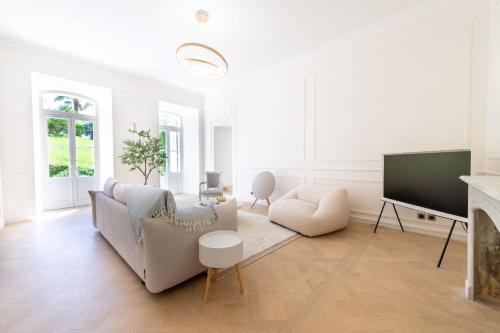 un salon blanc avec un canapé et une télévision dans l'établissement Garden-Level Apartment in Bourgeois Residence Near Croisette & Beaches, à Cannes
