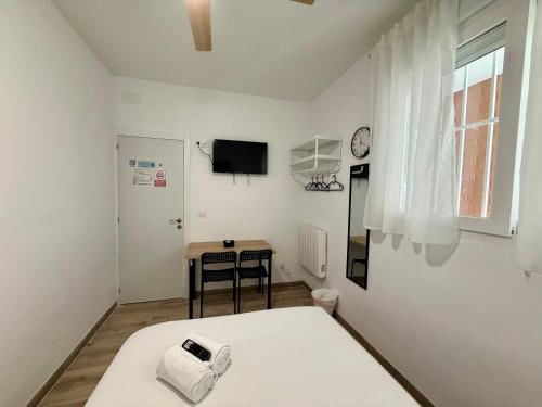 a white room with a bed and a table at Palomeras, Habitación de Ensueño in Madrid