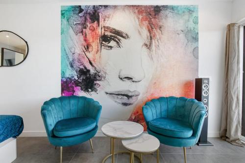 une pièce avec deux chaises bleues et un grand tableau dans l'établissement Blue moon Heliopolis, au Cap d'Agde