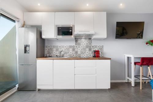  La cuisine est équipée de placards blancs et d'un réfrigérateur. dans l'établissement Blue moon Heliopolis, au Cap d'Agde