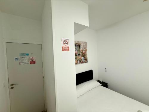 a small white room with a bed and a door at Palomeras, Habitación de Ensueño in Madrid