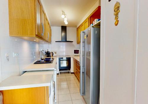 une cuisine avec des armoires en bois et un réfrigérateur en acier inoxydable dans l'établissement LILAS - Appartement pour 4 à proximité des commerces, à Capbreton