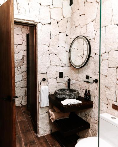 a stone bathroom with a sink and a mirror at Tulum Jungle Villa Tierra in Chemuyil