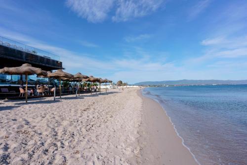 a sandy beach with umbrellas and the ocean at Paradise Home in Quartu SantʼElena